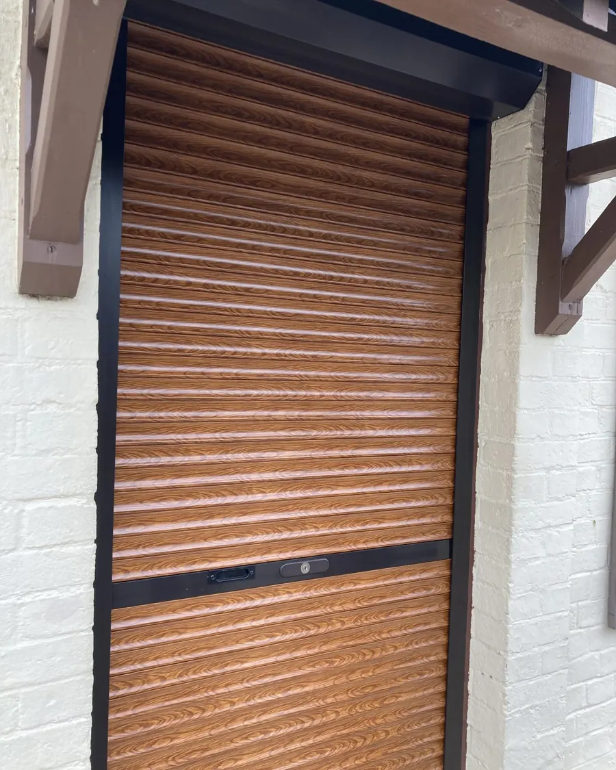 Volet roulant marron fermé sur une façade en brique