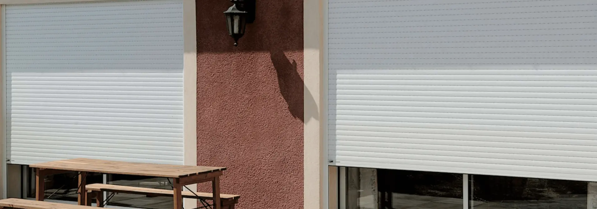 Volets roulants blancs fermés sur des baies donnant sur une terrasse